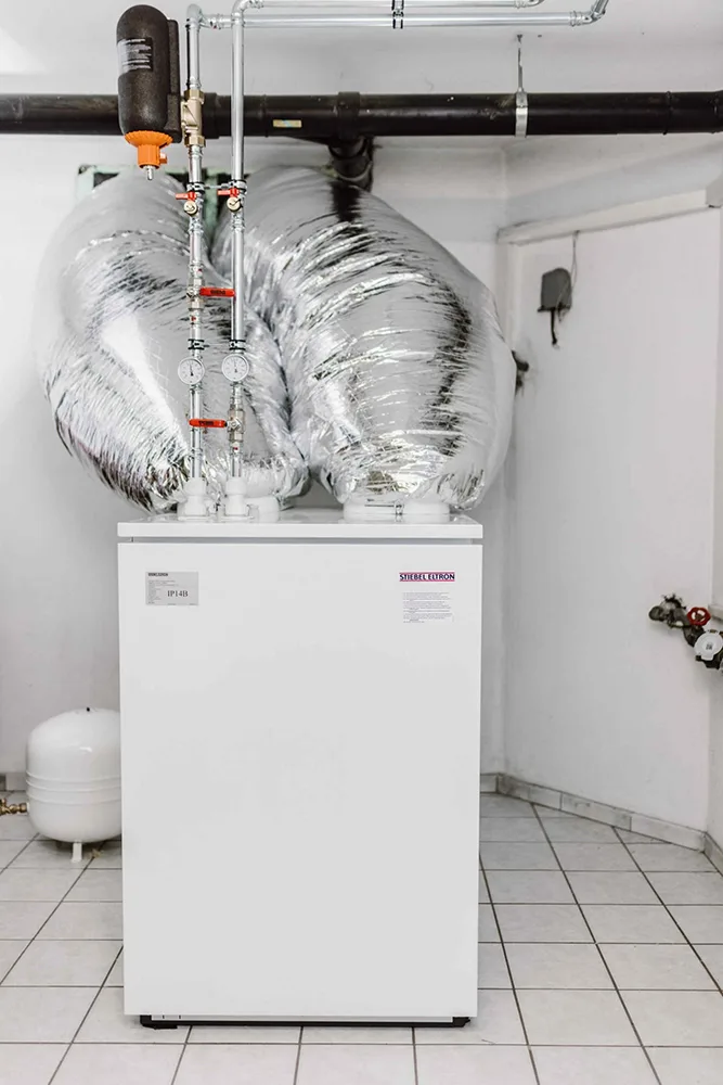 Stiebel-Eltron-Wärmepumpe mit silbern isolierten Luftkanälen im gefliesten Heizraum